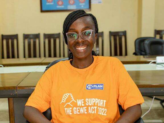 Blessing, 17, sitting in a chair wearing a Plan Internation t-shirt in Sierra Leone.