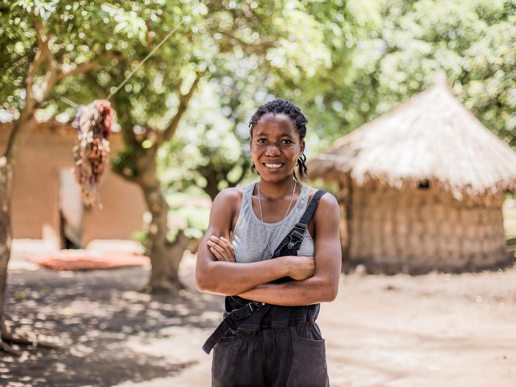Annette, 19, standing with her arms cross in a village in Zambia