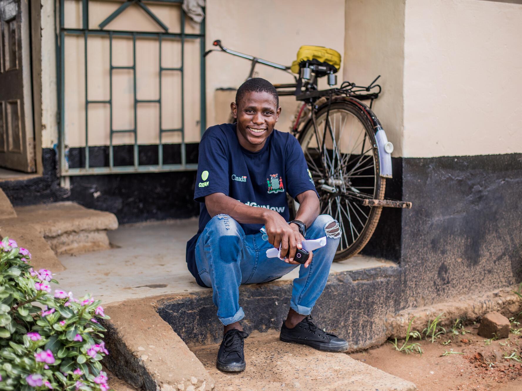 Boyd, 23, sitting on a step outside a building in Zambia