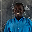 Winnie standing in front of chalk board at school in Kenya