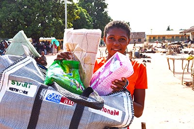 A young woman carrying a bag of supplies provided by Plan International