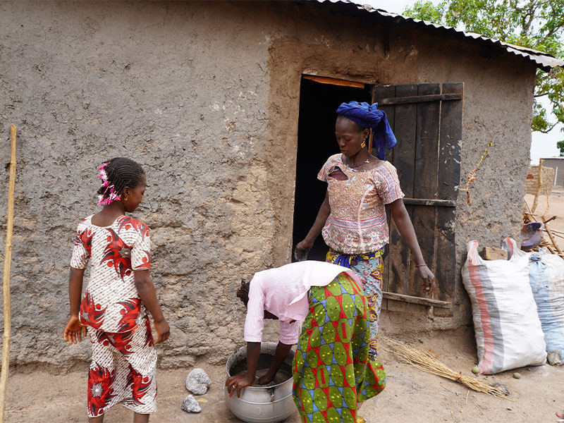 Diatour and her older sister helping their mother with chores outside.