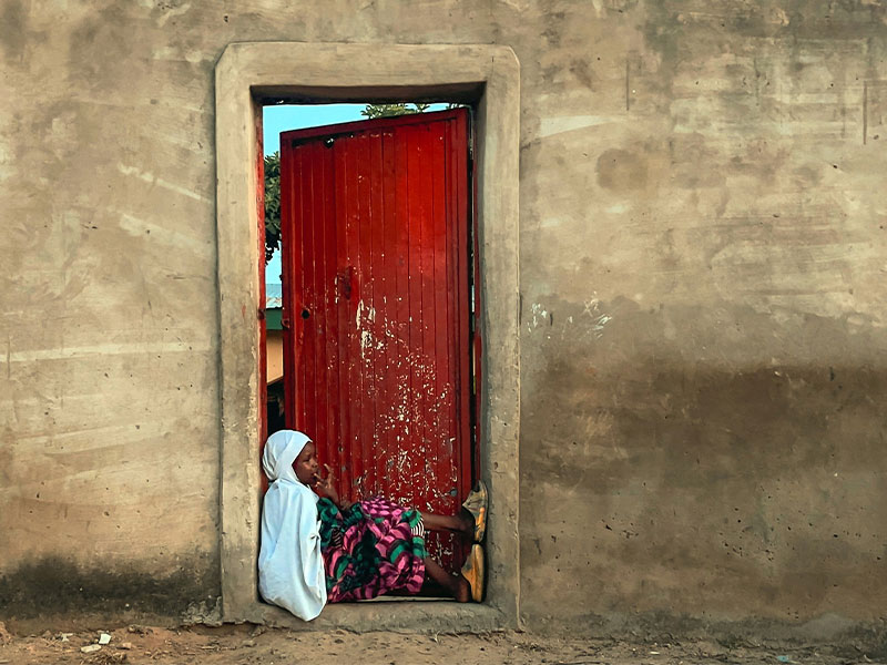 Young girl sitting in doorway looking out. 