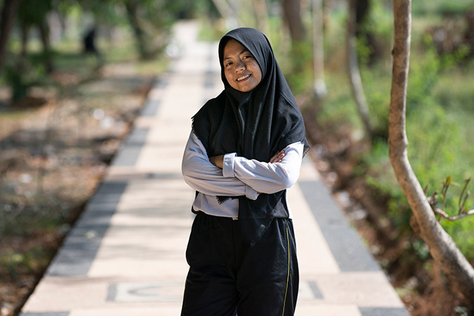 Indy, a young female peer educator in Indonesia, standing outside wearing a hijab