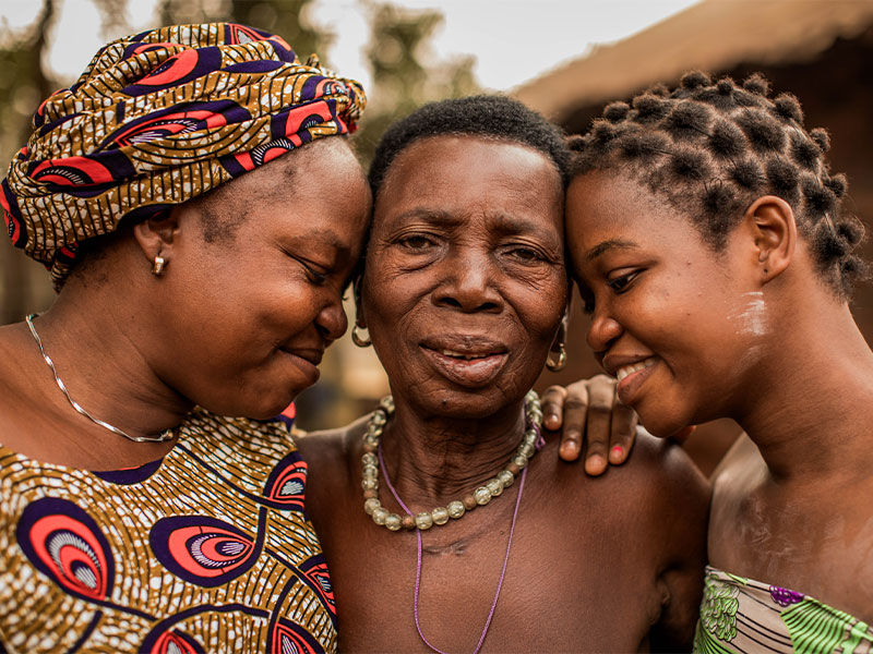 Grandmother being hugged by her daughter and granddaughter.