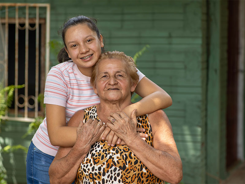 Alma hugging her grandmother who is sat down.