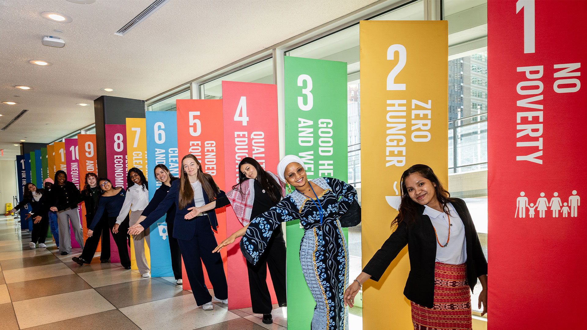 Young women standing in front of banners with sustainable development goal graphics