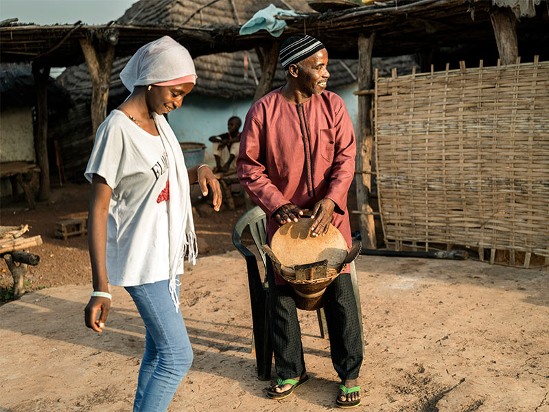 Fatou dancing as her father plays a tam tam