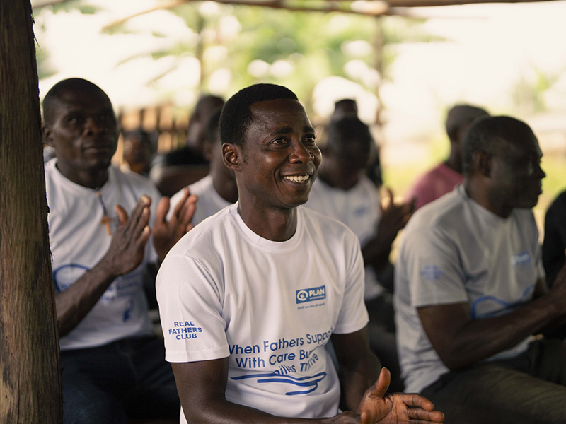 Michael, from Ghana, takes part in the Real Father's Club. He is smiling and listening to a talk.