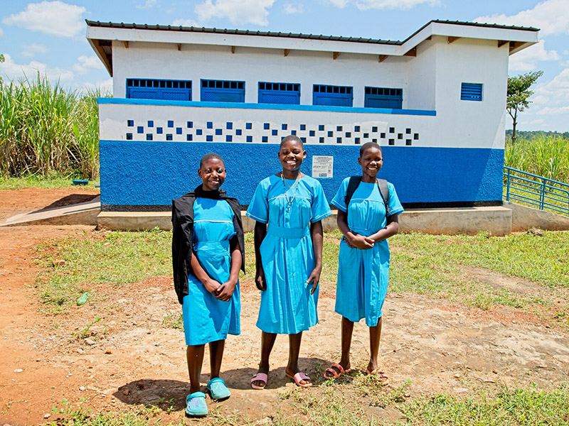 Robinah, 13, Ruth, 14, and Shadia, 13, in front of the new girls' toilet block.  