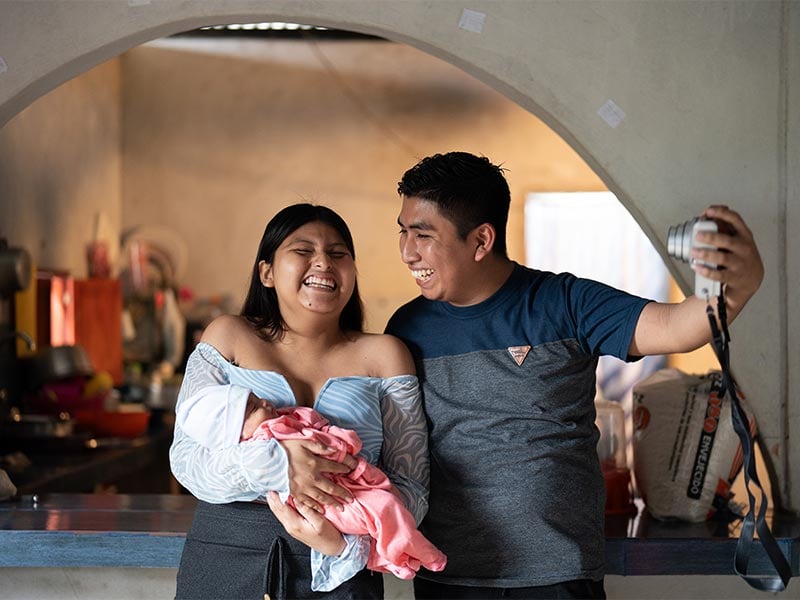 Leiver taking a photo of him, his wife and their newborn with a digital camera