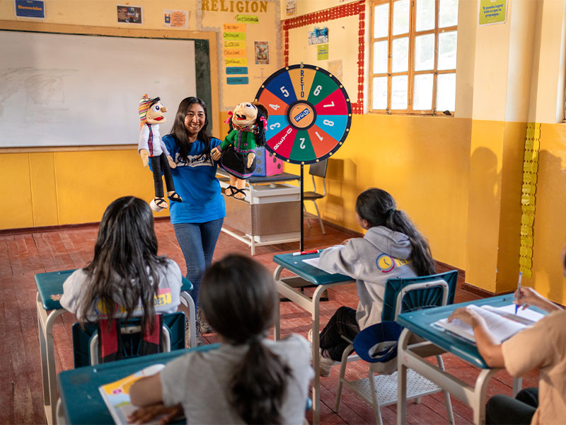 Mitzy stood at front of classroom of girls using puppets to teach them about gender-based violence prevention