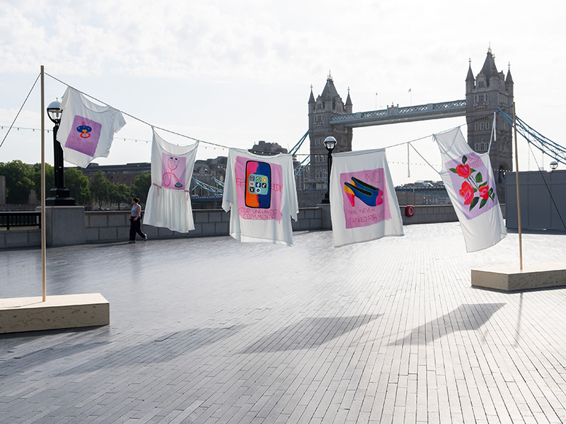 A washing line of clothes is suspended in front of Tower Bridge.