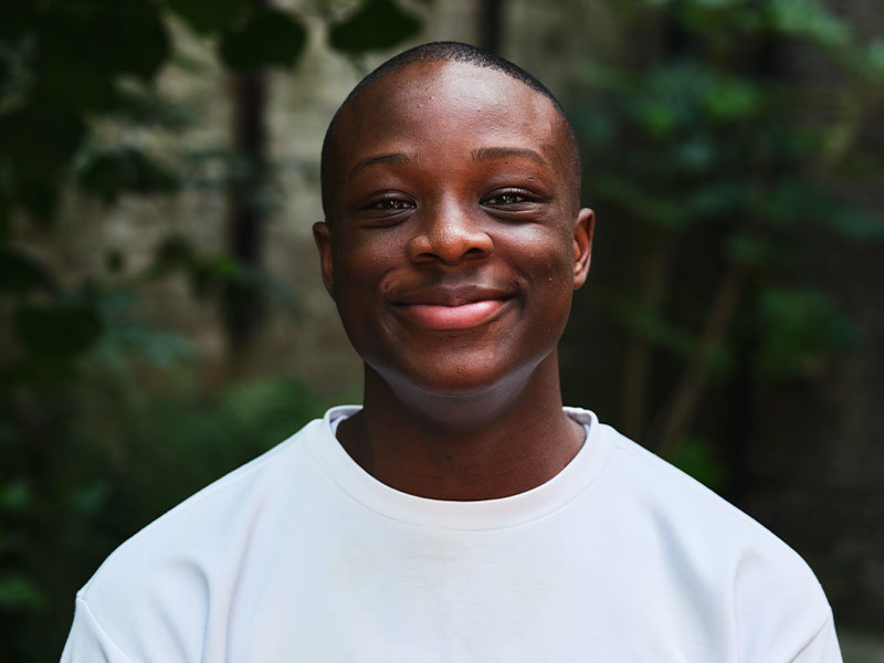 Headshot of Daniel standing outside with leaves in background