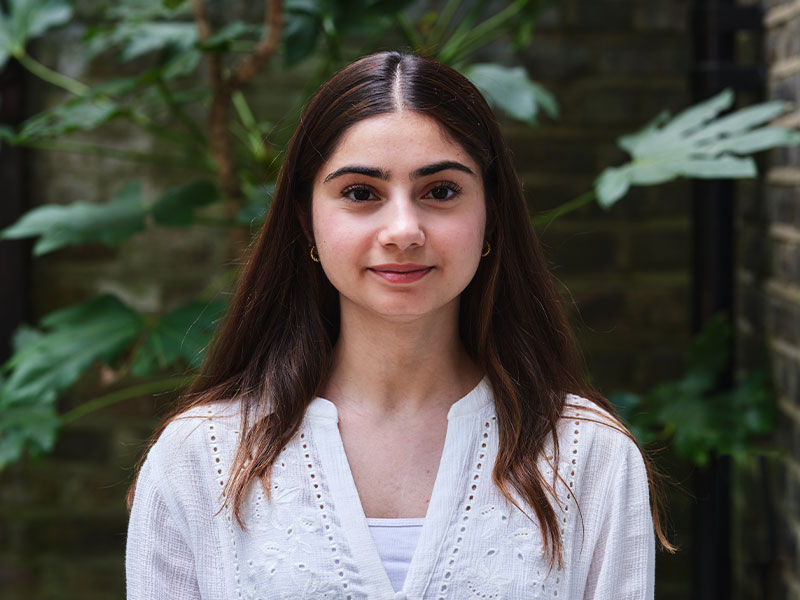 Headshot of Ealaf standing outside with leaves in background