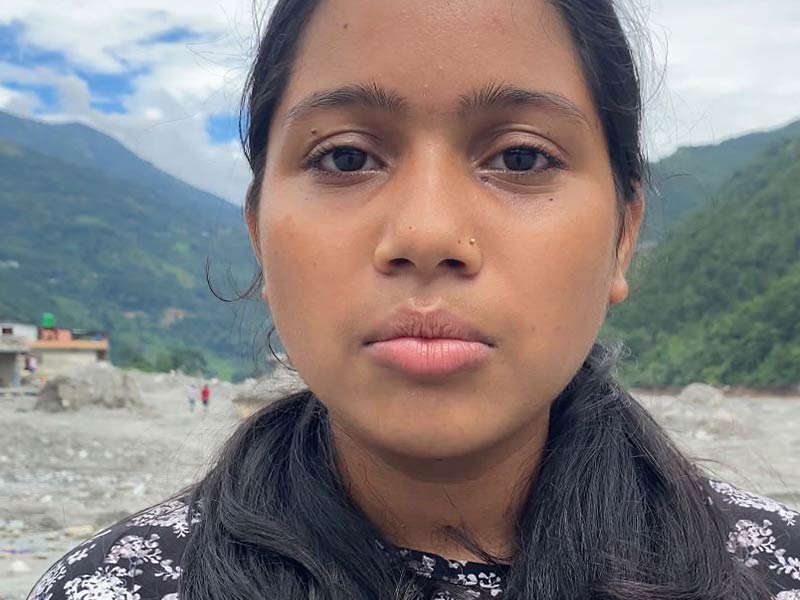 Aditi standing outside with rubble and mountains in background