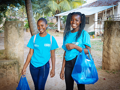 Two women attend a training centre set up by Plan International. They are carrying bags of supplies.