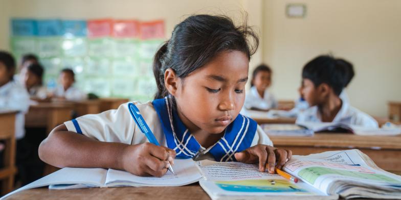 Len Sokha, 10, studying from books in a school classroom in Cambodia