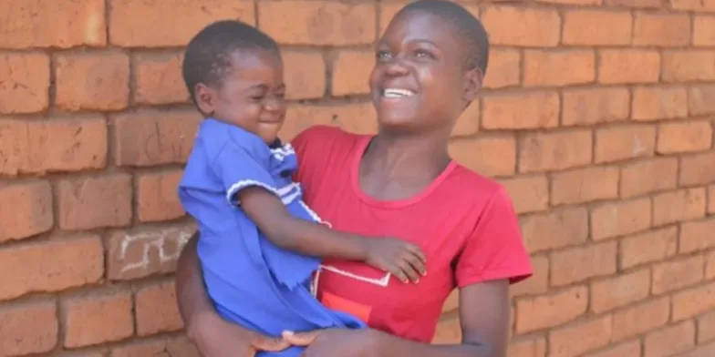 Ethel holding her daughter. The background is a brick wall