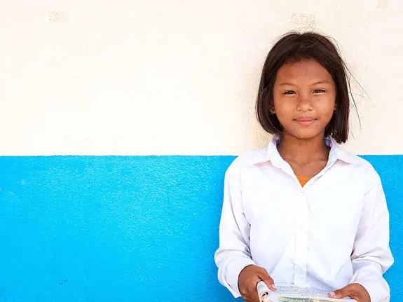 Muta, 11, standing in front of a white and blue wall.