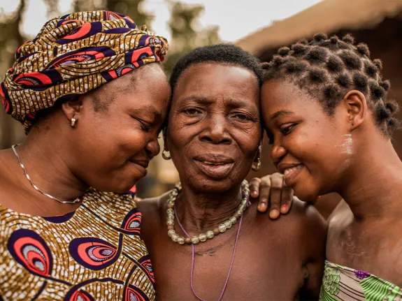 Grandmother being hugged by her daughter and granddaughter. 