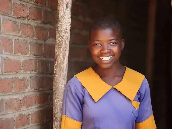 Irene, 13, standing in front of brick wall wearing her school uniform