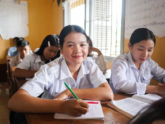 Phgnon and classmates at school and writing in notebooks at desks