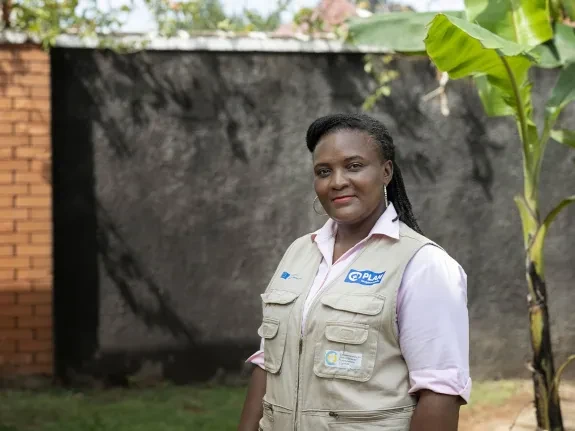 Christine standing outside wearing Plan International branded uniform. 
