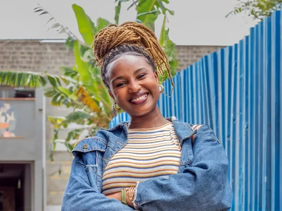 Latifah stands with folded arms. She is smiling at the camera.
