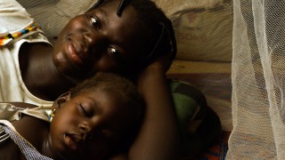 Mariam and her daughter Rachidatu under the mosquito net they share at their home