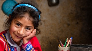 Zenaida, 6, uses the radio to do her schoolwork at home in Cusco