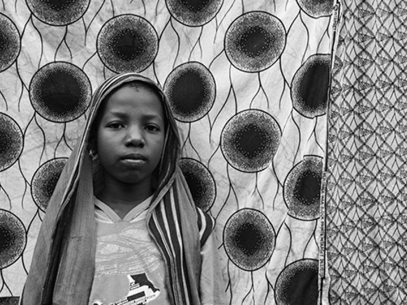 Ghana-Ayisha stands before a traditional piece of Ghanaian cloth on the clothing line in the compound