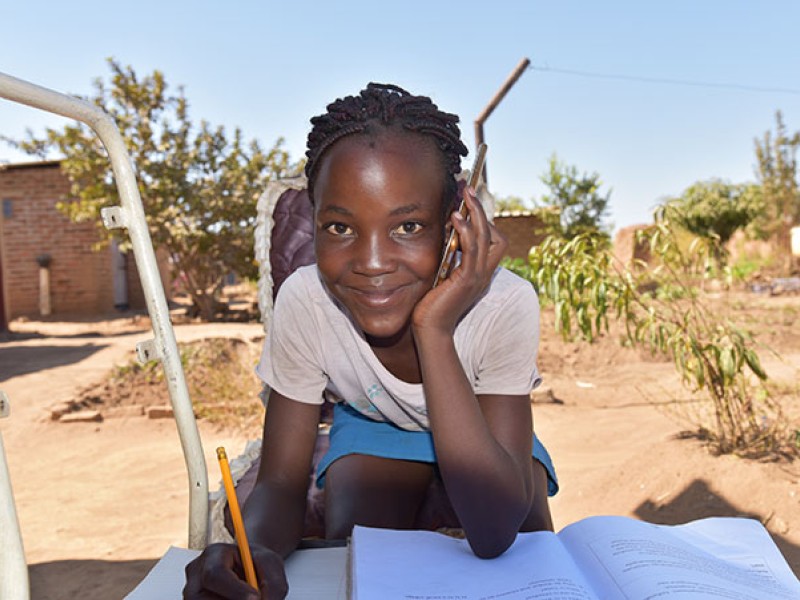 A girl with a mobile phone and school books