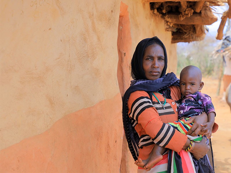 Sara, 35, with her youngest daughter Lelo next to their home
