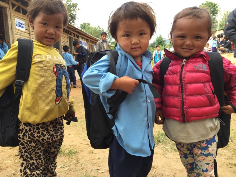 Children stand outside a school built by Plan International