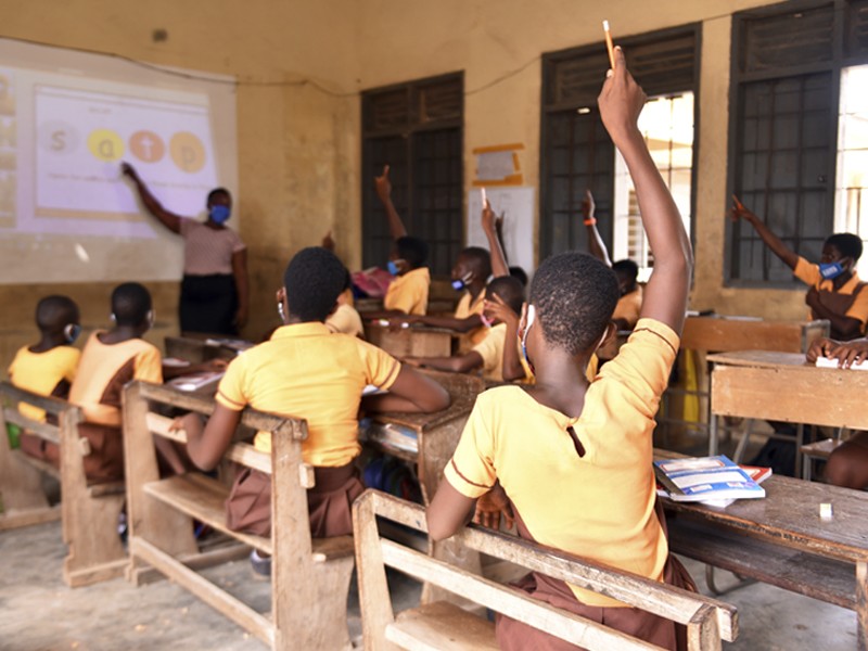 Girls raise their hands in a classroom in Ghana