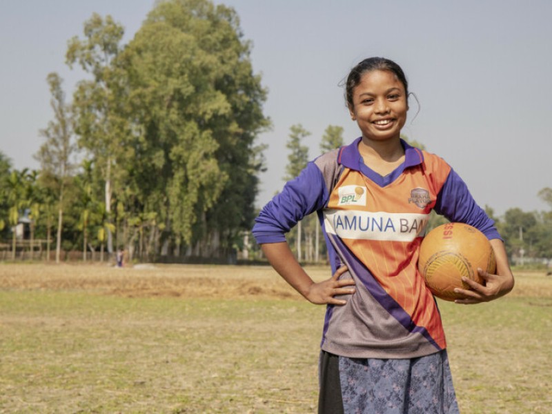A girl smiling holding a football