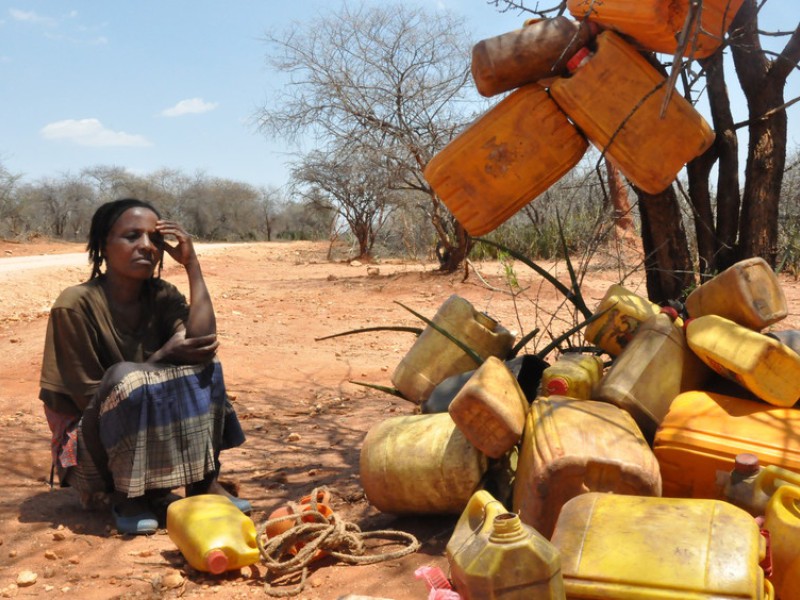 Woman waits by the road side waiting for a water delivery to arrive in Ethiopia