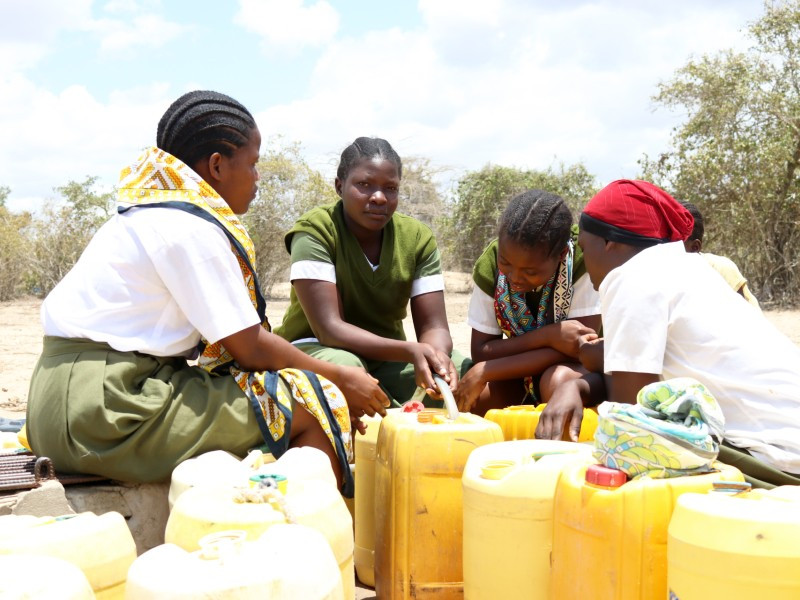 Jenitor with other girls collecting water using jerry cans 