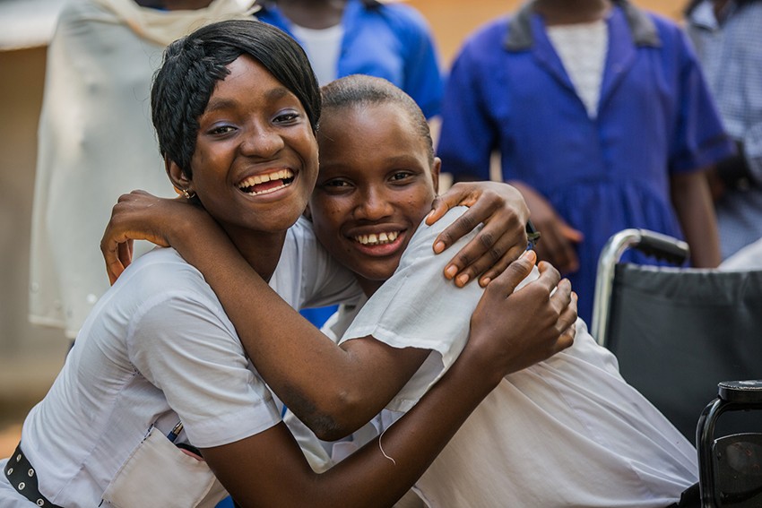 Baromie hugs her friend during break at a Plan-supported school in Sierra Leone