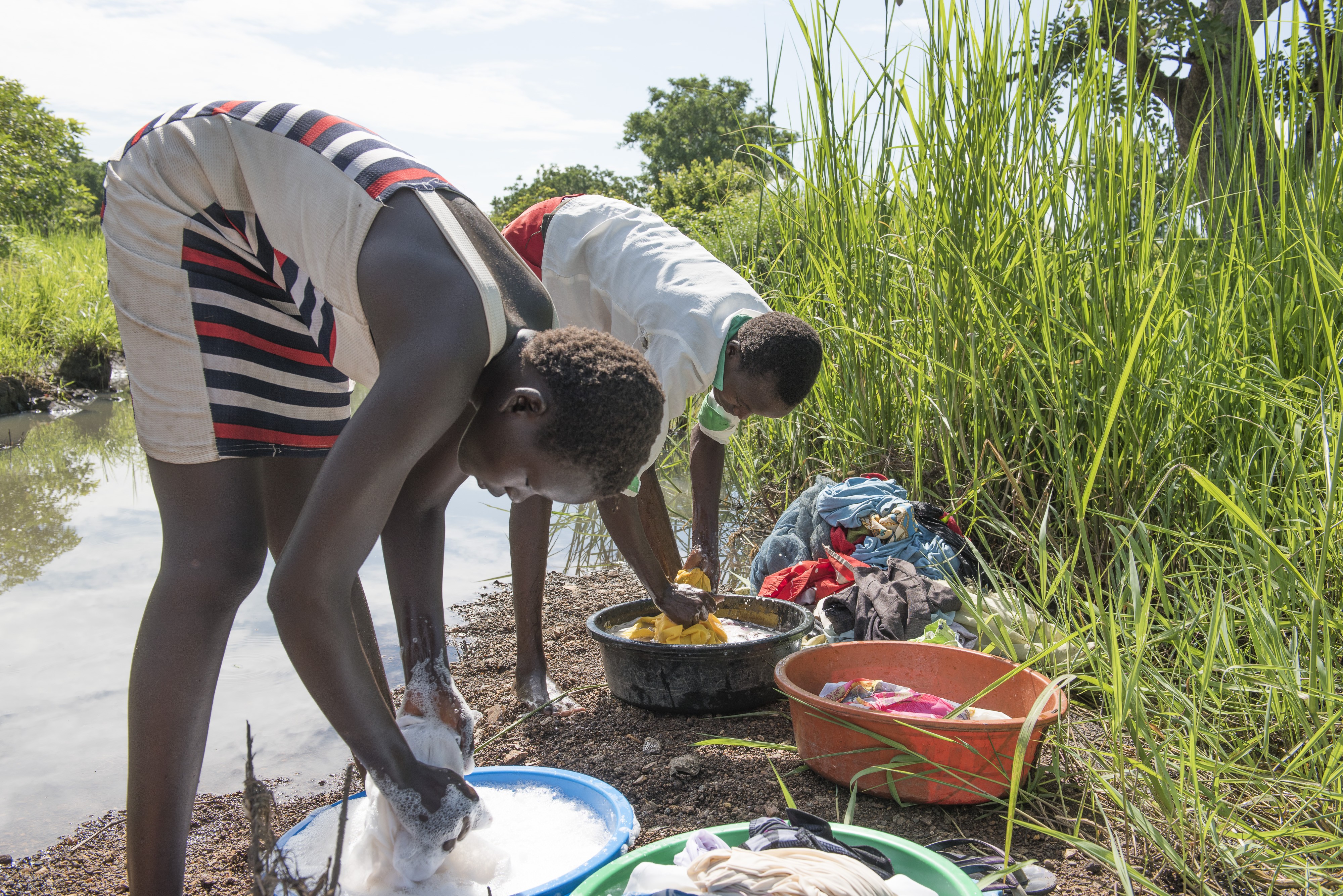 Girls wash clothes next to the river in South Sudan