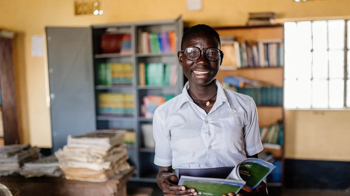 Moreen, 19, reads one of the books from her school library in Uganda.