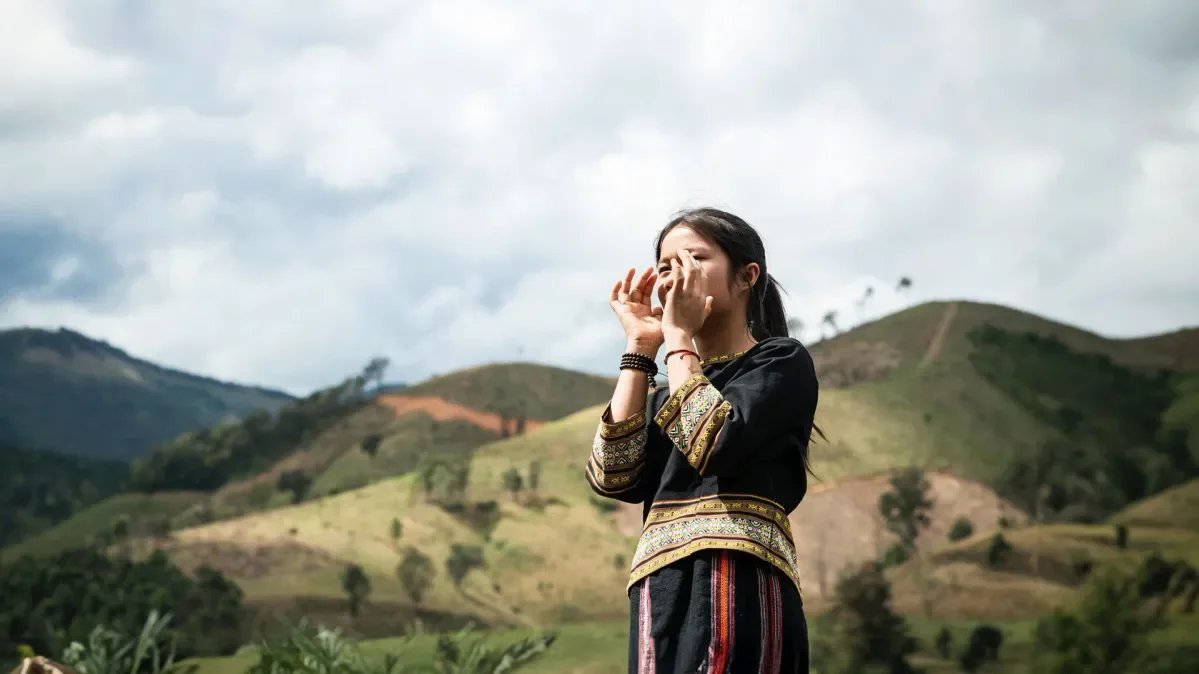 Y Kieu calling through her hands with green hills in background