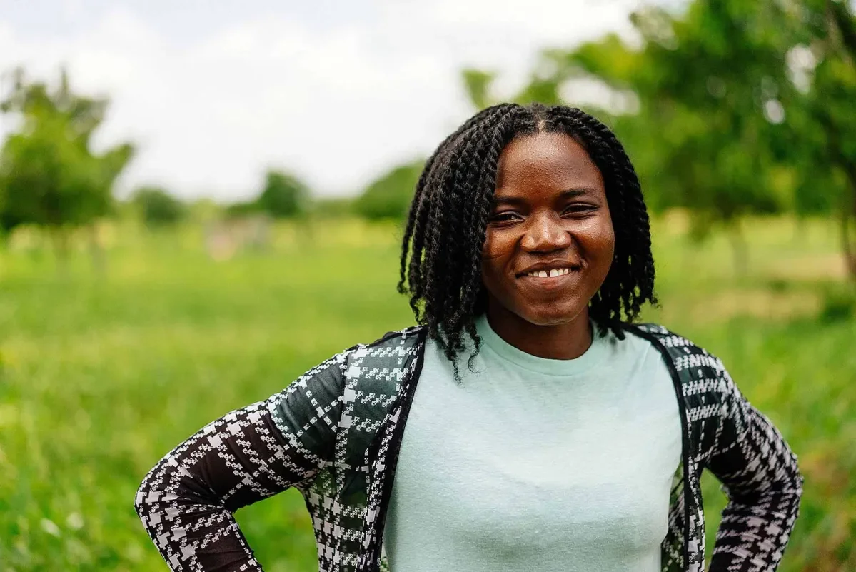 Doris, 27, a maize and soybean farmer, standing in a field on her farmland