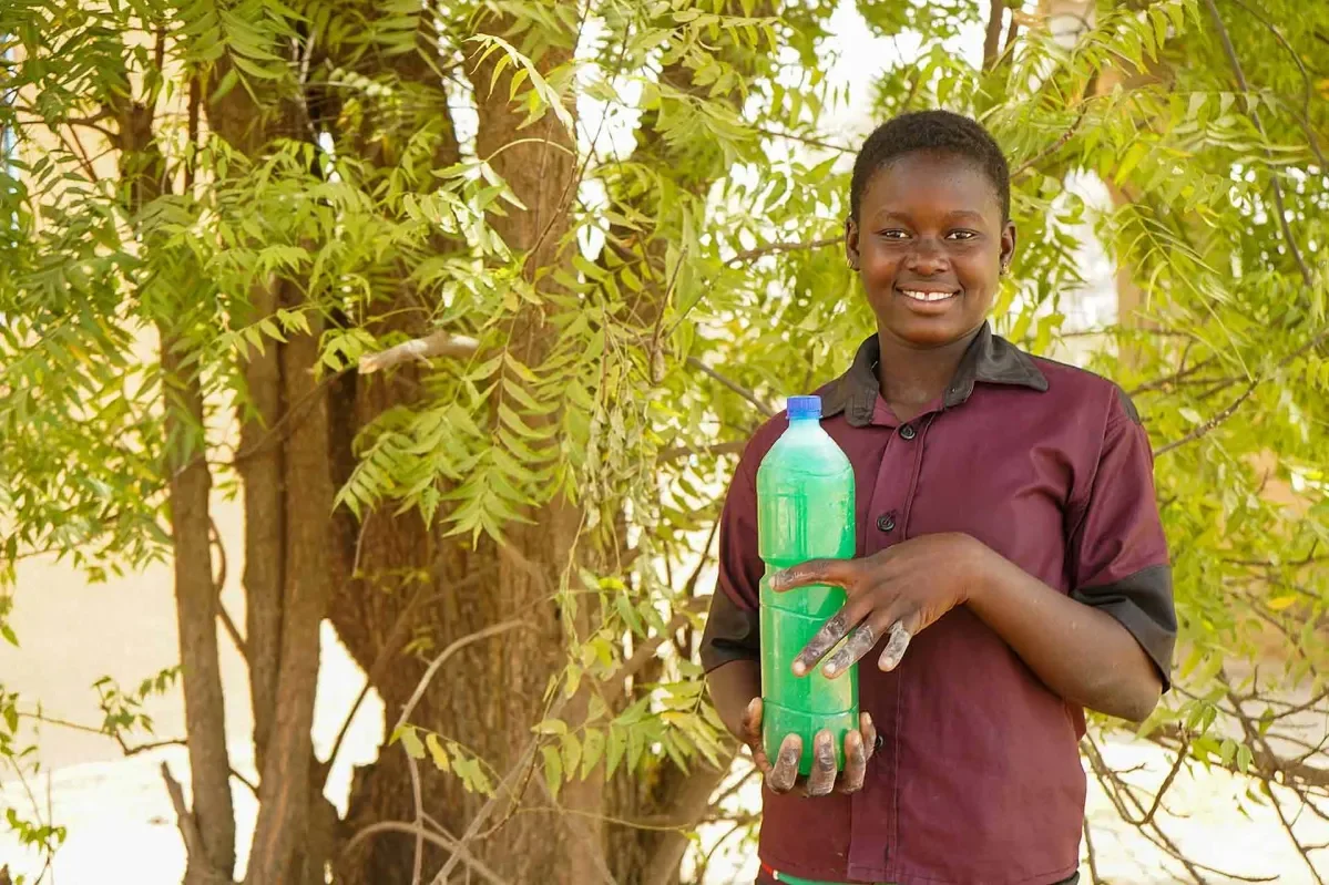 Jemima, 18, holding a bottle of the liquid soap she makes in Burkina Faso. 