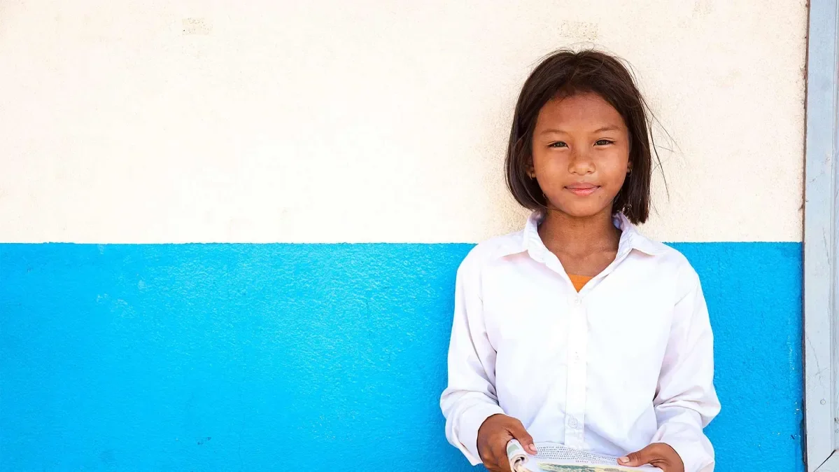 Muta, 11, standing in front of a white and blue wall.