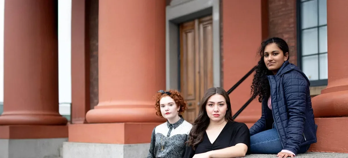 Three young women from the UK sitting in a group.