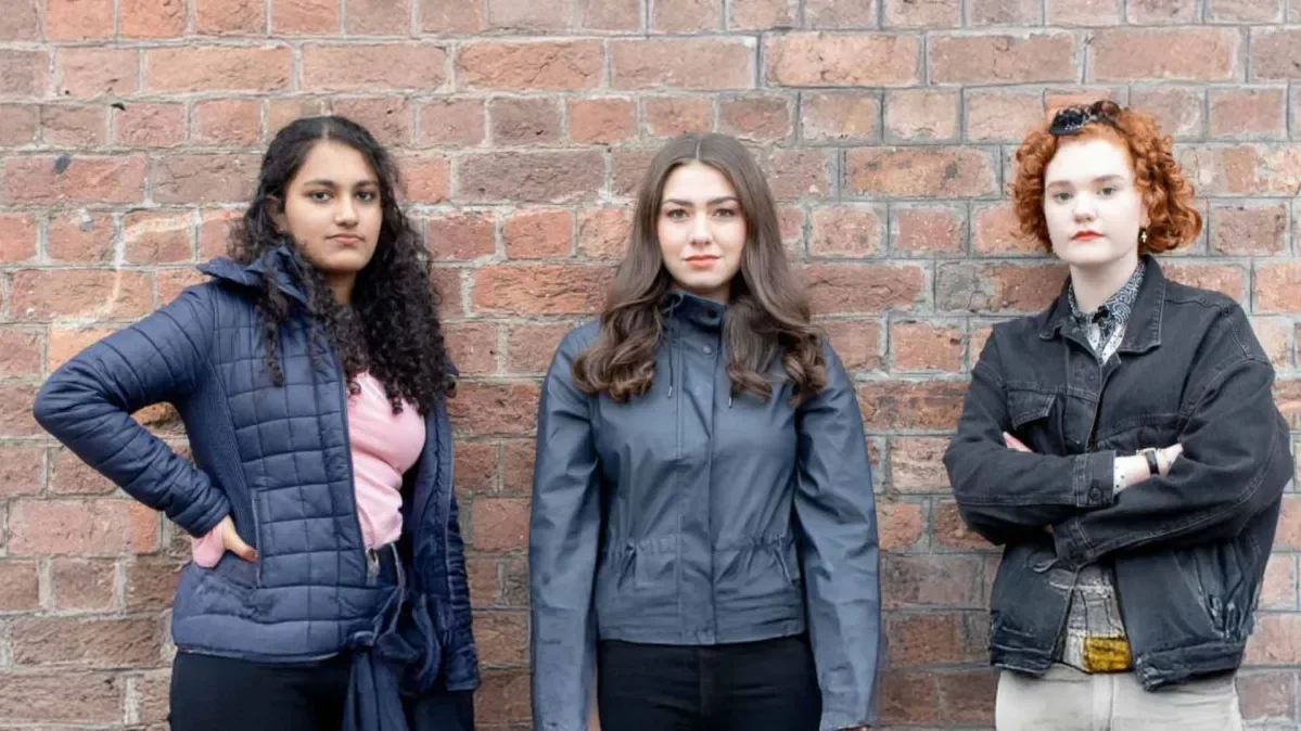 Three young female campaigners standing in front of brick wall