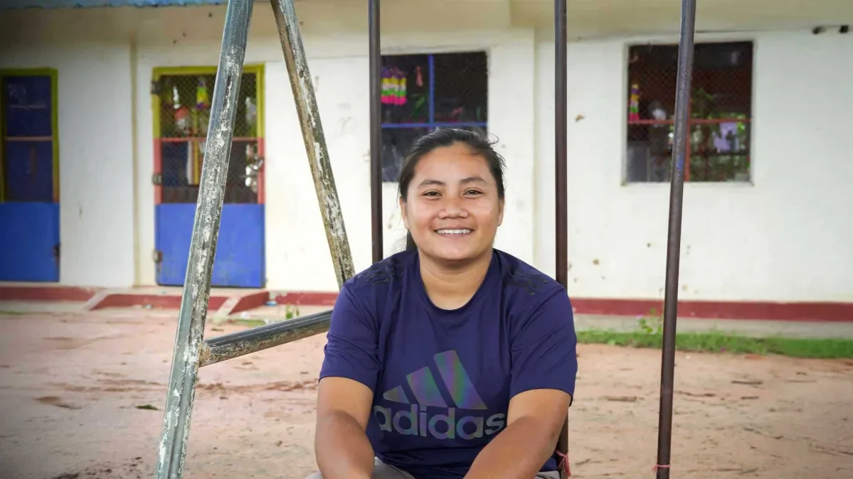 Ousa sat outside a school smiling at camera.