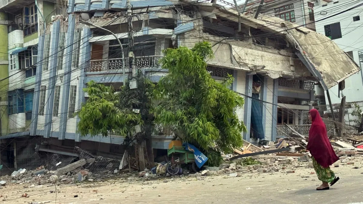 Badly damaged building in the aftermath of the devastating earthquake in Myanmar with woman walking past.